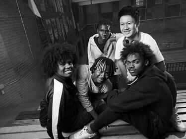 five students sitting on bleachers in the gym 